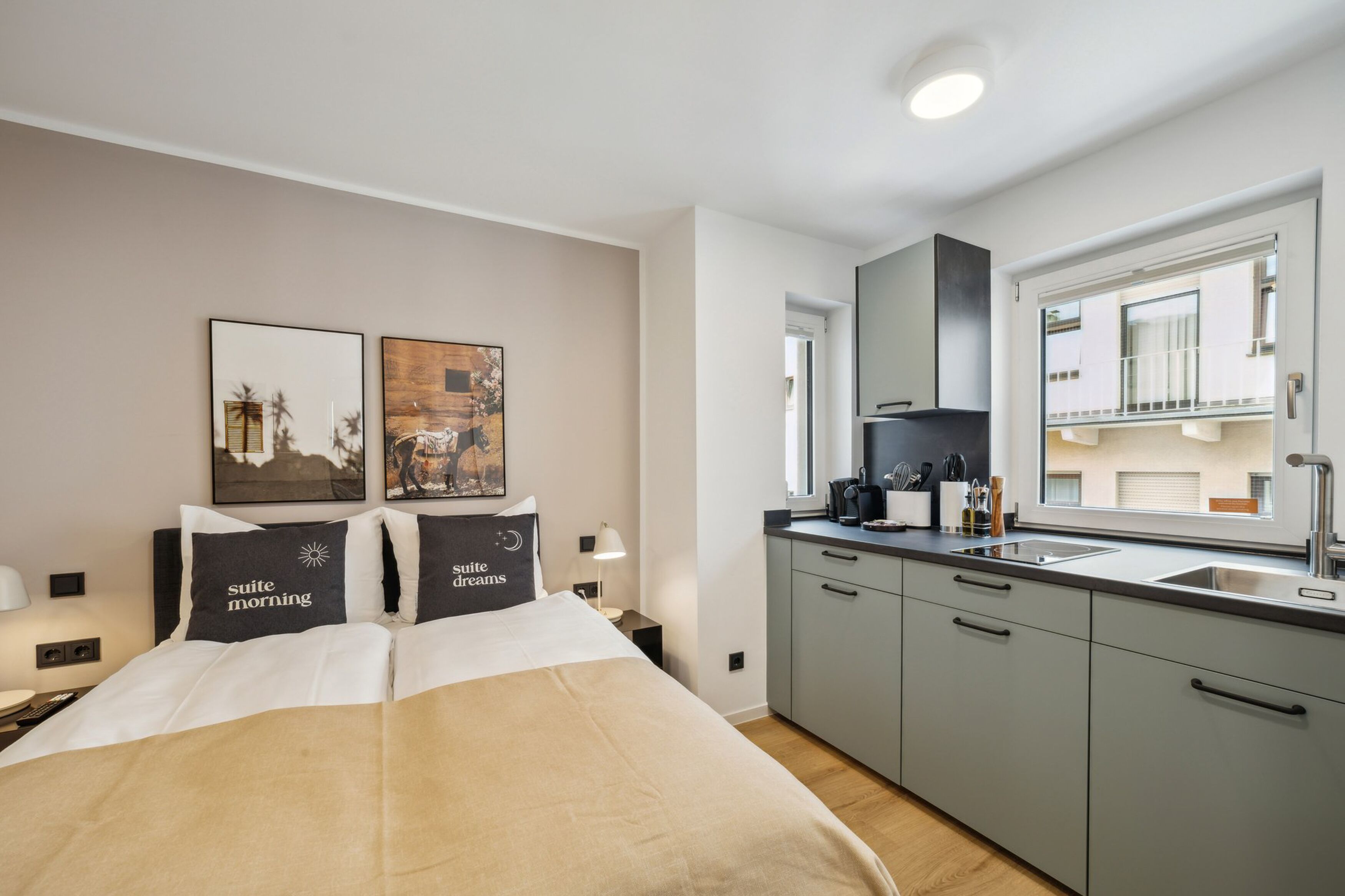 Ein Hotelzimmer mit Bett, Nachttisch, Schreibtisch, einem Fenster mit Blick und einer Küchenzeile.