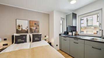 Ein Hotelzimmer mit Bett, Nachttisch, Schreibtisch, einem Fenster mit Blick und einer Küchenzeile.