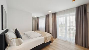 Un dormitorio moderno con cama, mesitas de noche y un amplio ventanal con cortinas.