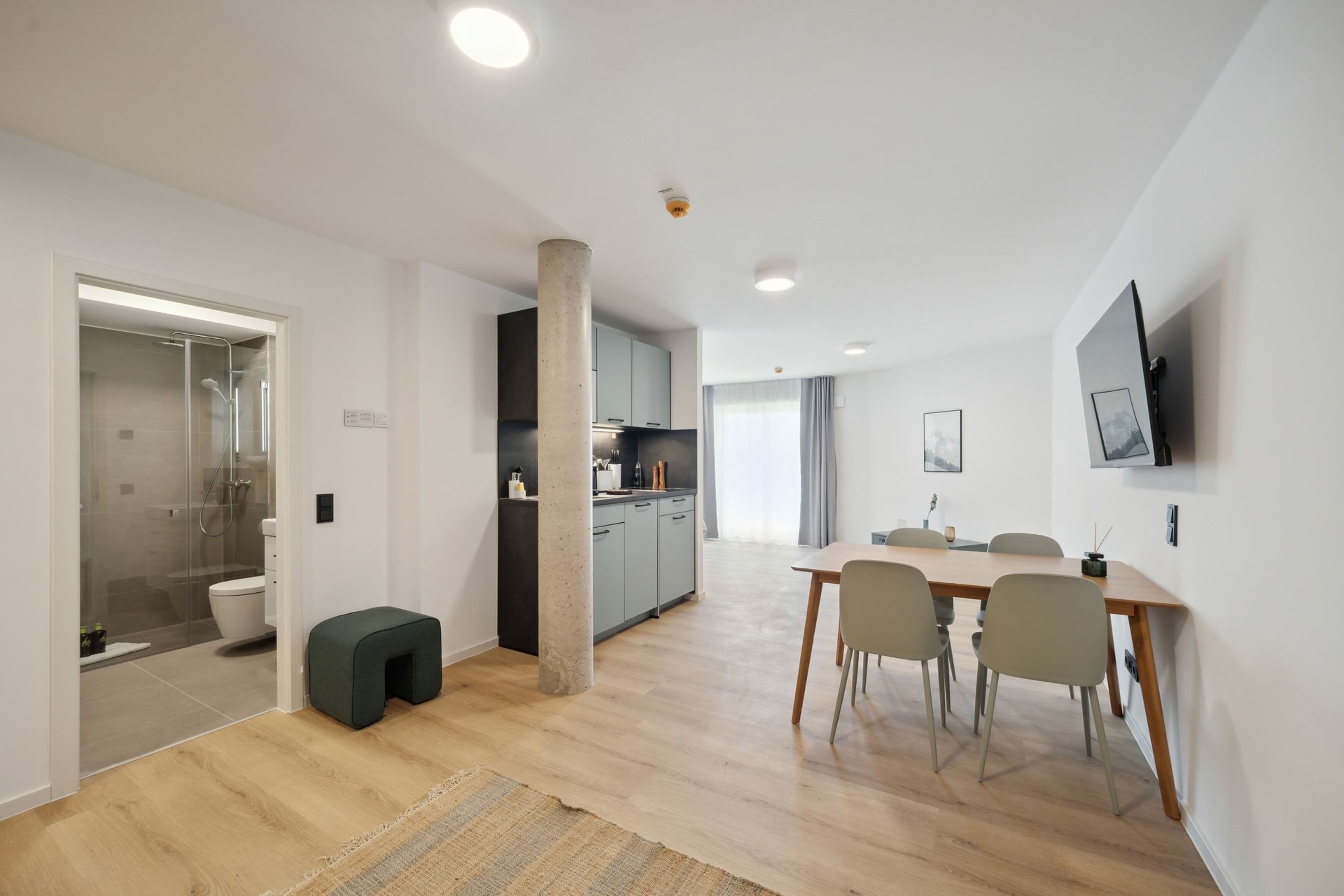 Een modern appartement met keuken, eethoek en badkamer met douche.