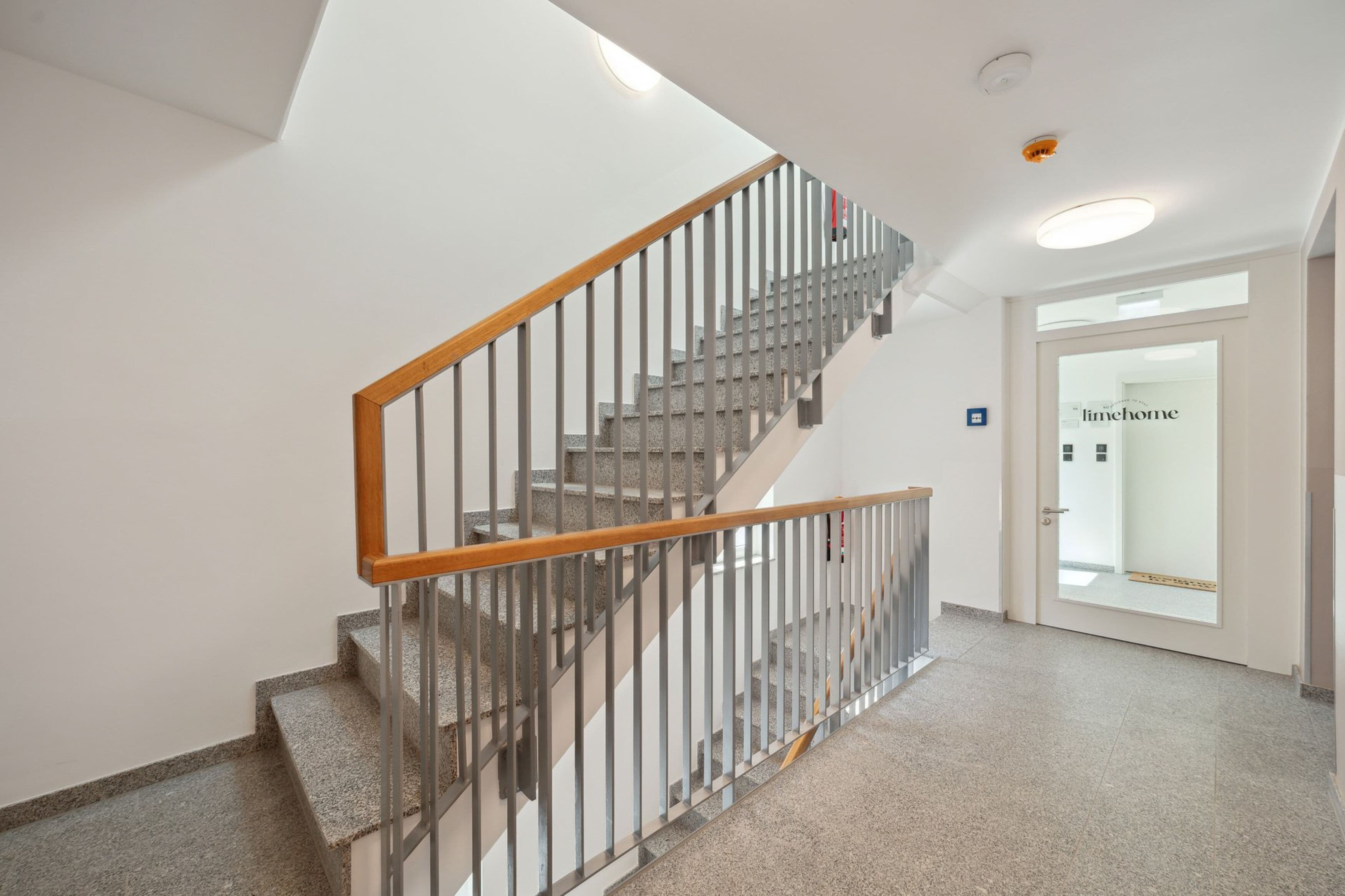 A modern interior with a staircase, a door labeled "timehome," and a clean, well-lit hallway.