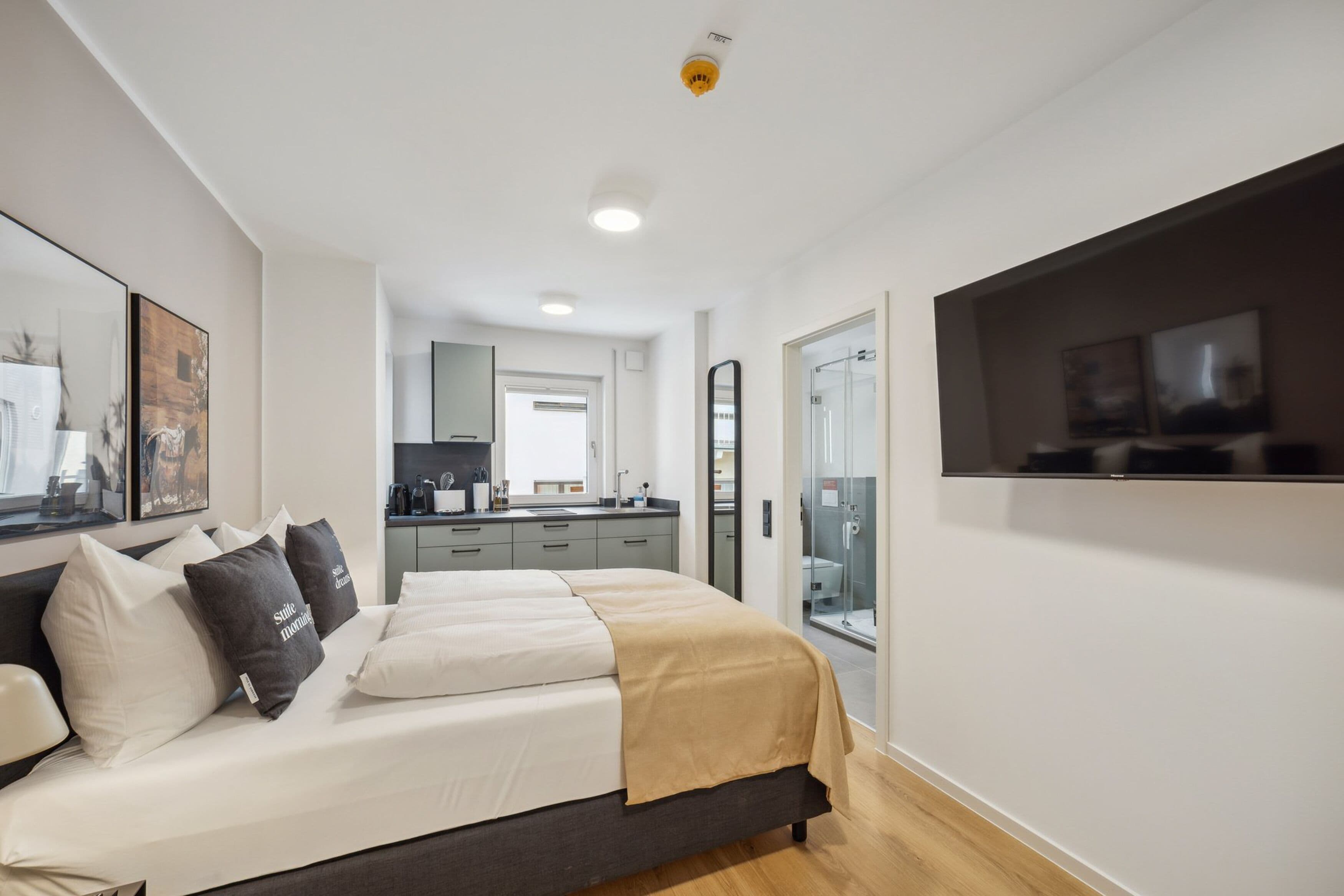 A modern bedroom with a bed, bedside tables, and a TV mounted on the wall.