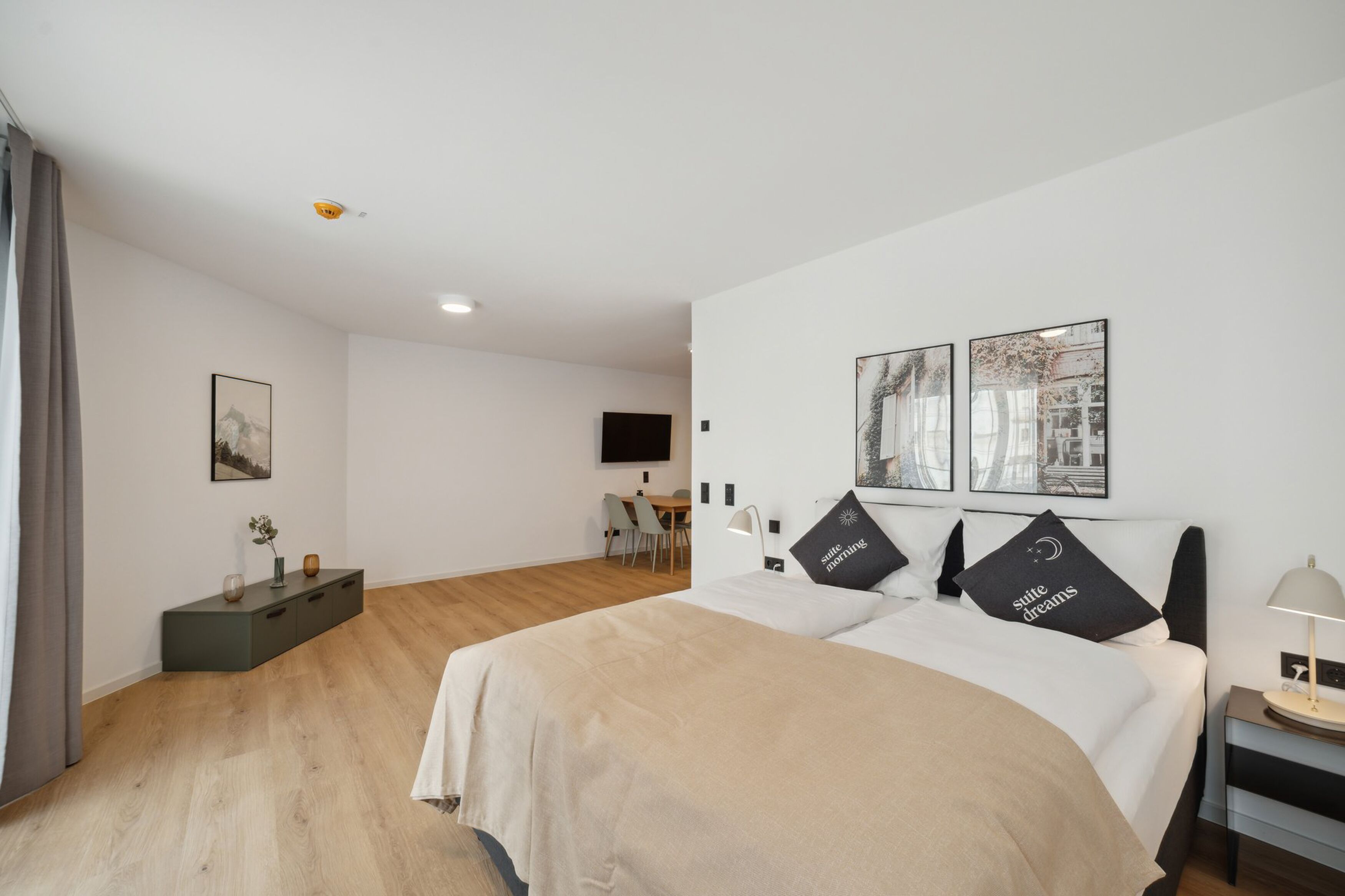 Une chambre d’hôtel moderne équipée d’un lit, de tables de chevet, d’un bureau et d’un téléviseur fixé au mur.