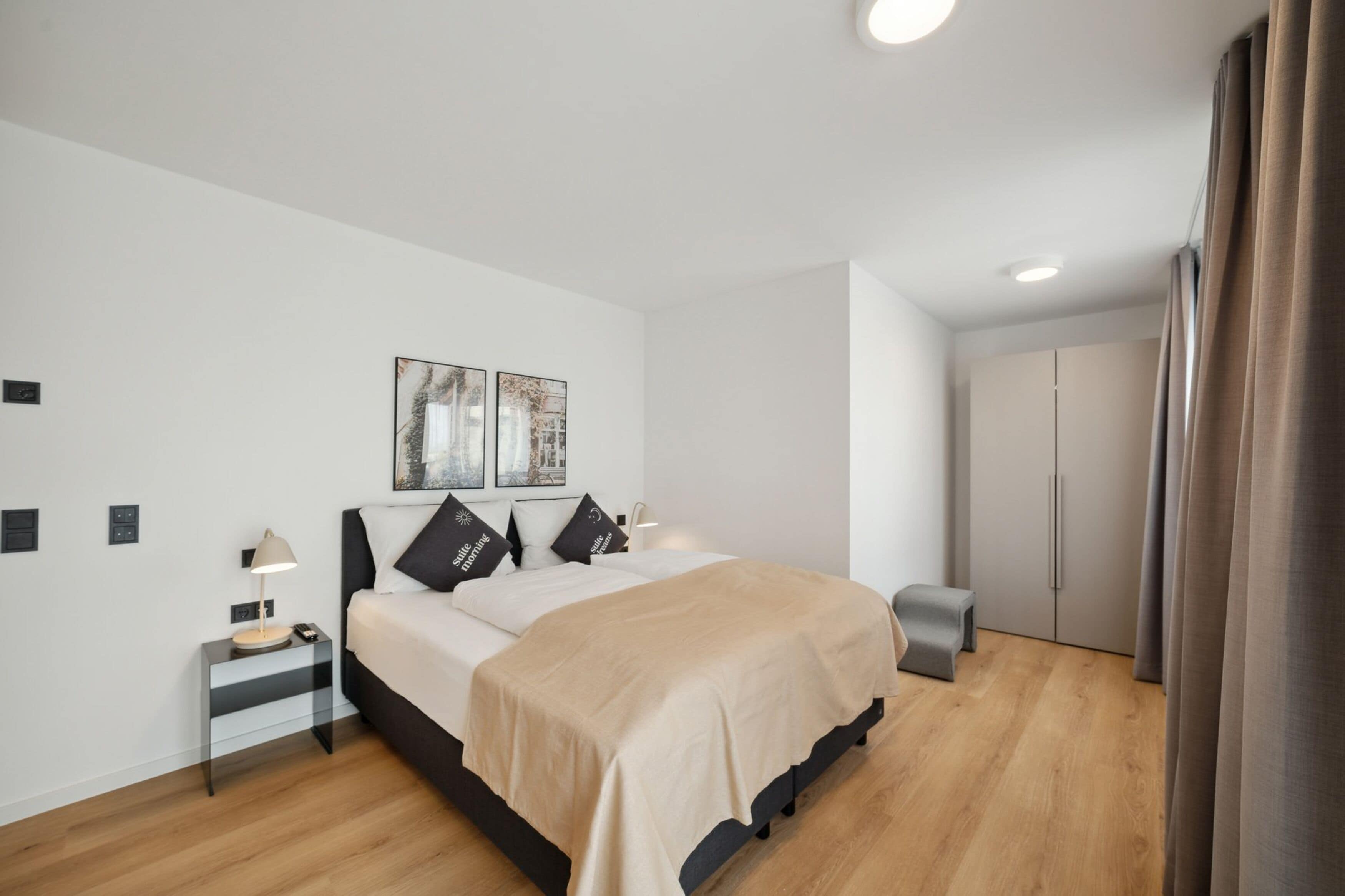 Ein modernes Schlafzimmer mit Bett, Nachttischen, Kleiderschrank und Spiegel.