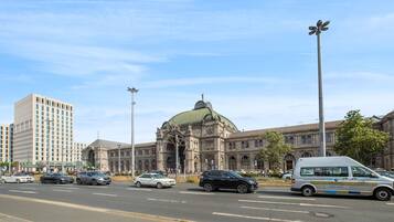 Eine Straße mit Autos und einem Lieferwagen, ein großes Gebäude mit Kuppel und eine hohe Straßenlaterne.