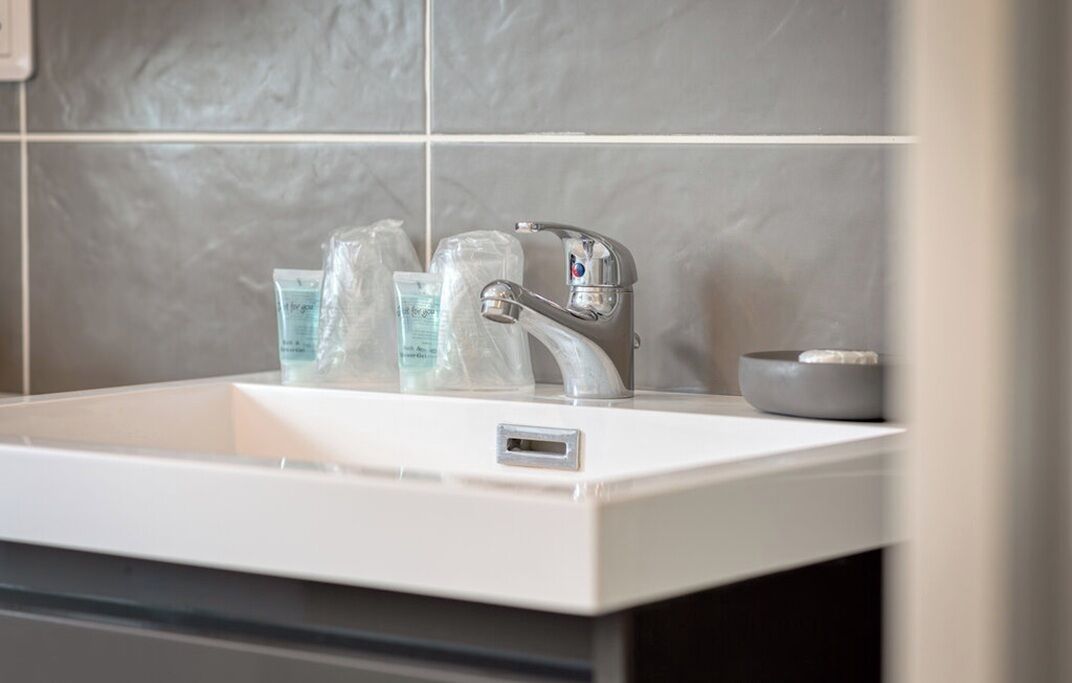 A modern bathroom with a white sink, a silver faucet, and a small bowl.