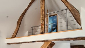 Un espacio habitable estilo loft con vigas de madera a la vista, una escalera, un sofá y una mesa de centro.