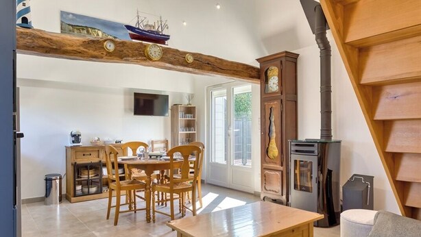 Una cocina acogedora con muebles de madera, una mesa de comedor y un gran reloj en la pared.