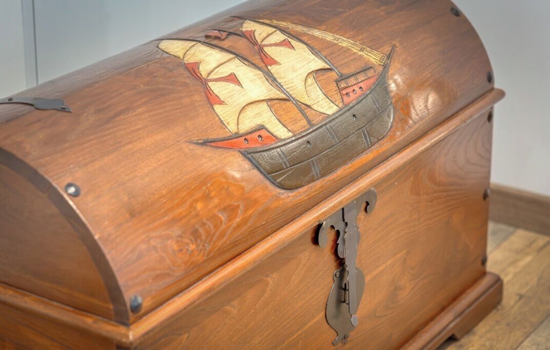 Une boîte en bois dont le couvercle est décoré d’un motif représentant un navire.