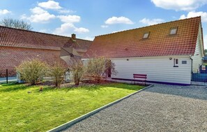A building with a red-tiled roof, a white exterior, and a gravel driveway. There is a bench and a small garden area with shrubs. - Clos Marie-Louise
Meublé 3 étoiles (OFFRANVILLE)