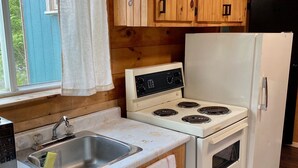 Eine kleine Küche mit Holzschränken, einem weißen Herd und einem Kühlschrank.