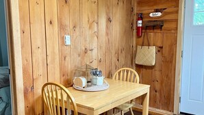 Ein Holzkaminzimmer mit Esstisch und Stühlen, einem Feuerlöscher und einer Tür mit dem Schriftzug 'Hello'.