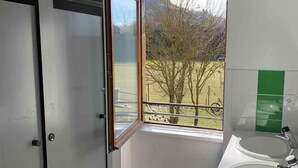 A bathroom with a window, a sink, and a door. - Auberge de jeunesse HI Millau La Maladrerie (Millau)