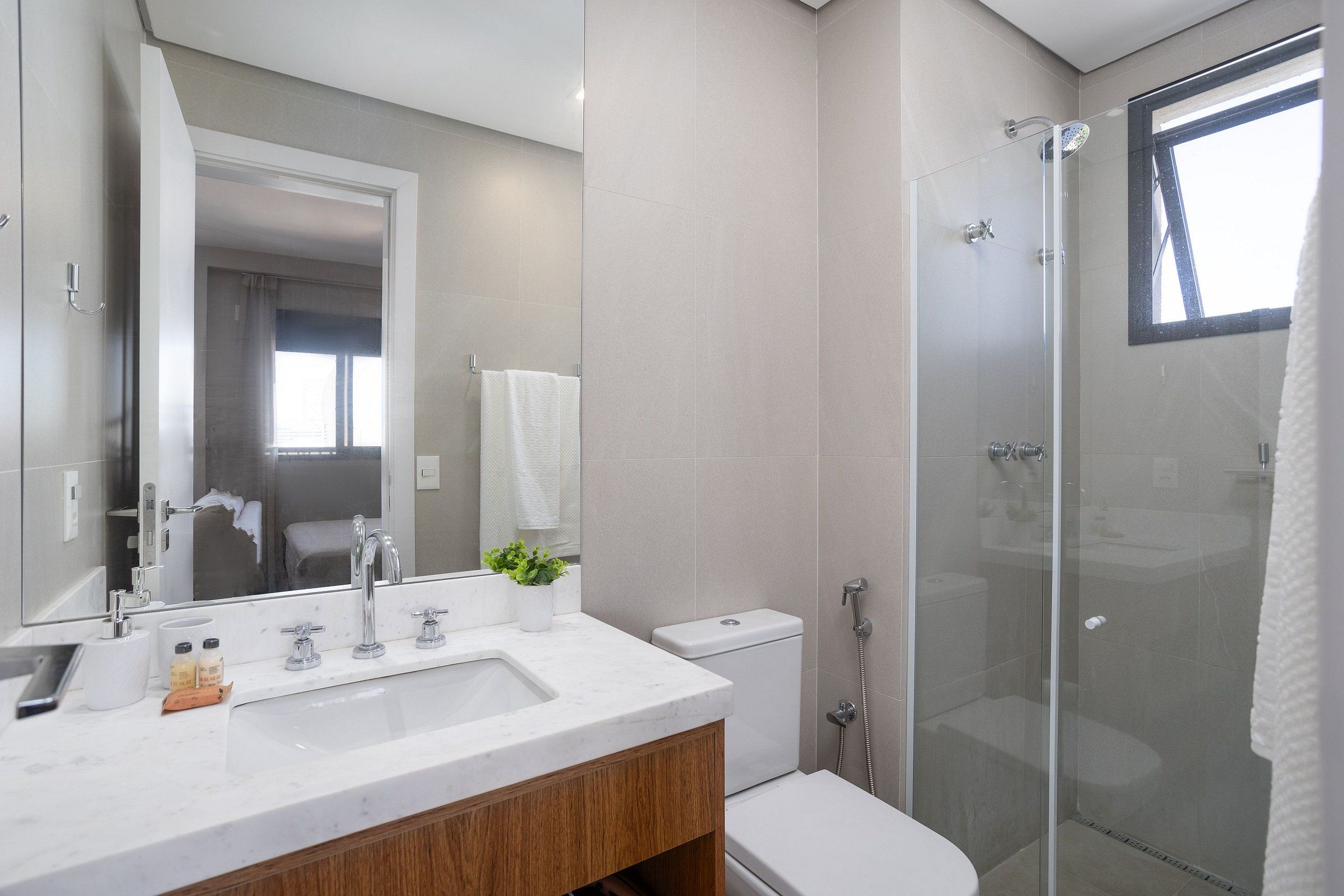 A modern bathroom with a glass shower enclosure, a white sink, and a mirror.