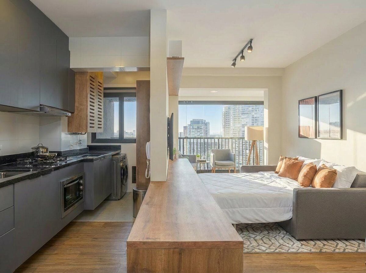 Uma cozinha moderna com uma ilha central, uma sala de jantar com uma mesa comprida, um sofá e uma varanda com vista para a cidade.