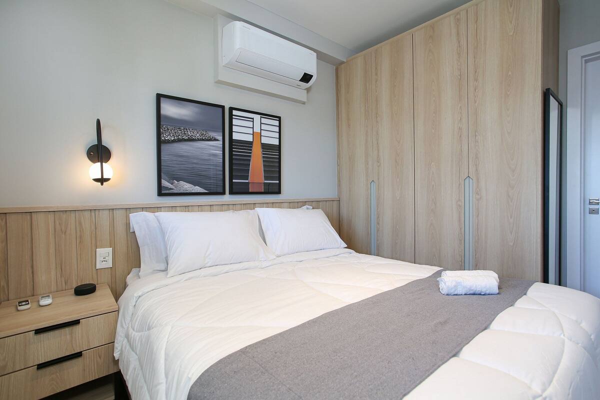 Ein modernes Schlafzimmer mit Bett, Nachttischen, einer Klimaanlage und Kunstwerken an der Wand.