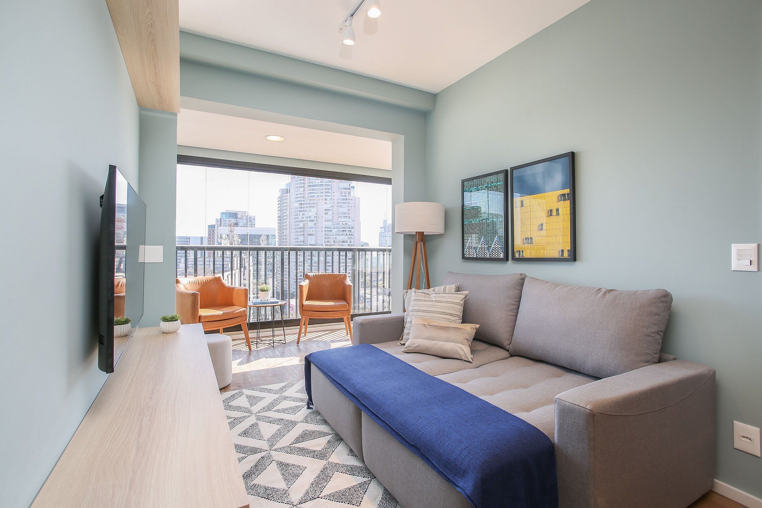Un salon moderne avec un canapé, une table basse, un téléviseur et un balcon offrant une vue sur la ville.