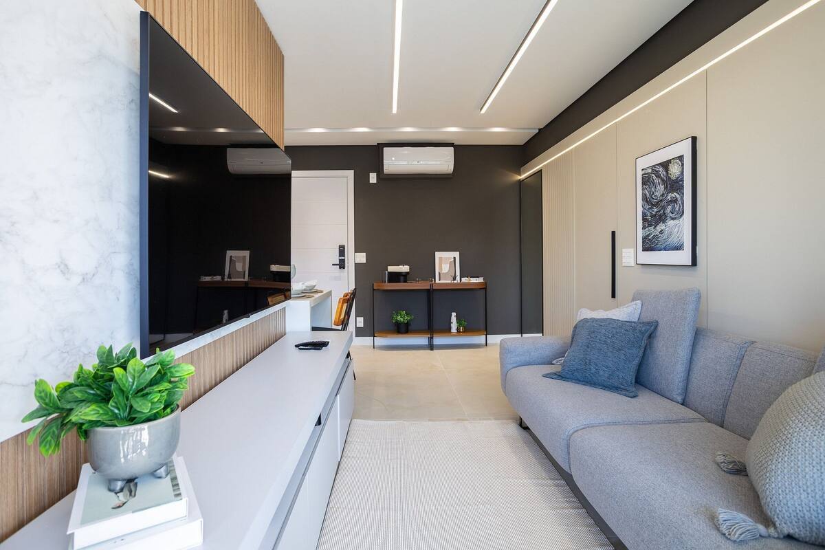 Ein modernes Wohnzimmer mit einem grauen Sofa, einem weißen Couchtisch mit einer Pflanze und einem gerahmten Kunstwerk an der Wand.