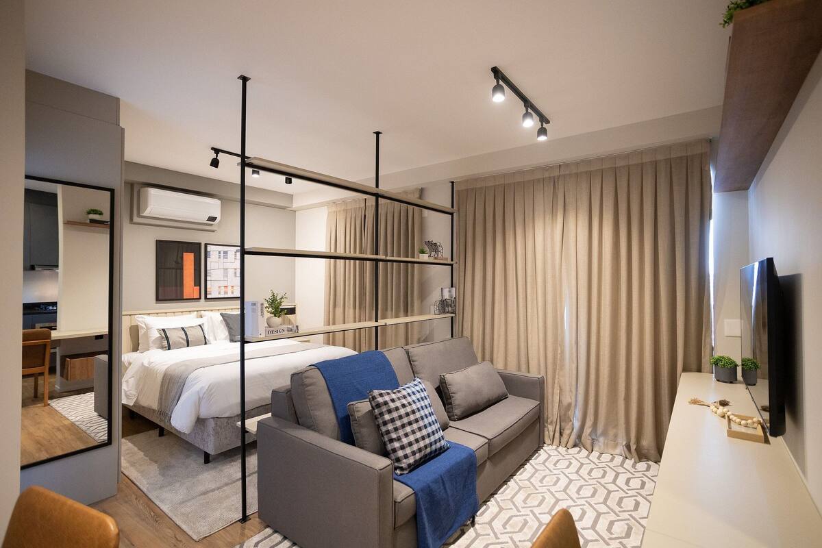 Ein modernes Hotelzimmer mit Bett, Sofa und Schreibtisch.