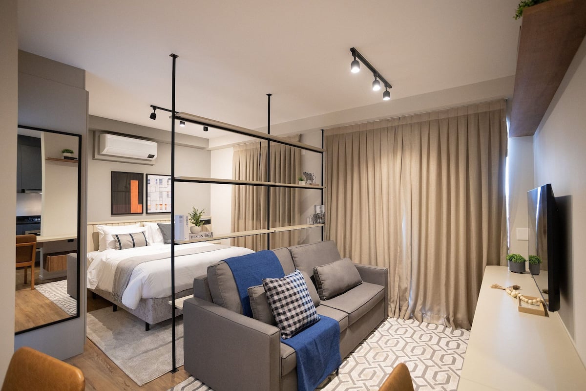 A modern hotel room with a bed, sofa, and desk area.
