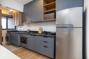 A modern kitchen with grey cabinetry, a built-in oven, a microwave, and a stainless steel refrigerator. - Expand Pinheiros (São Paulo)