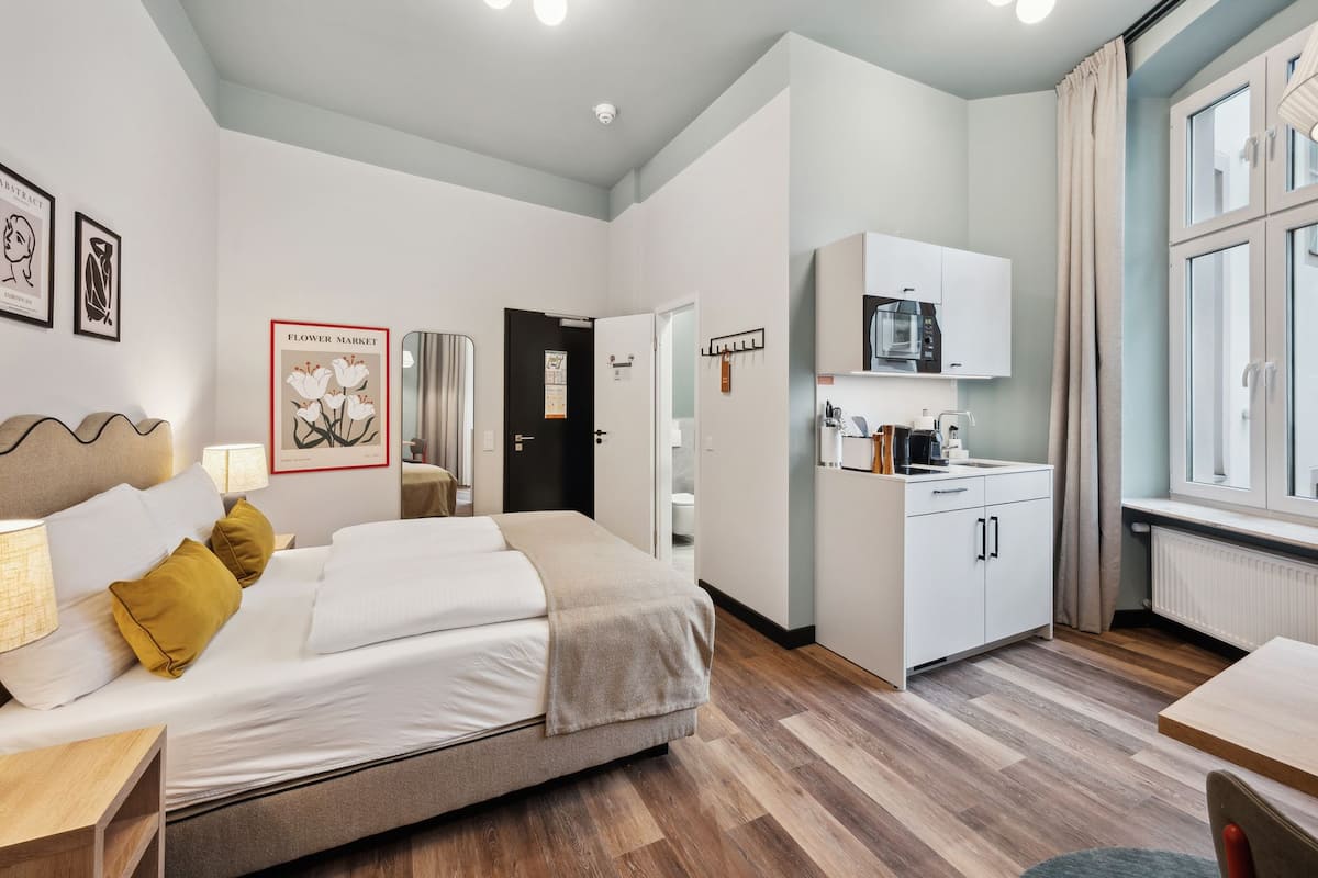Una habitación de hotel moderna con cama, mesita de noche y kitchenette.