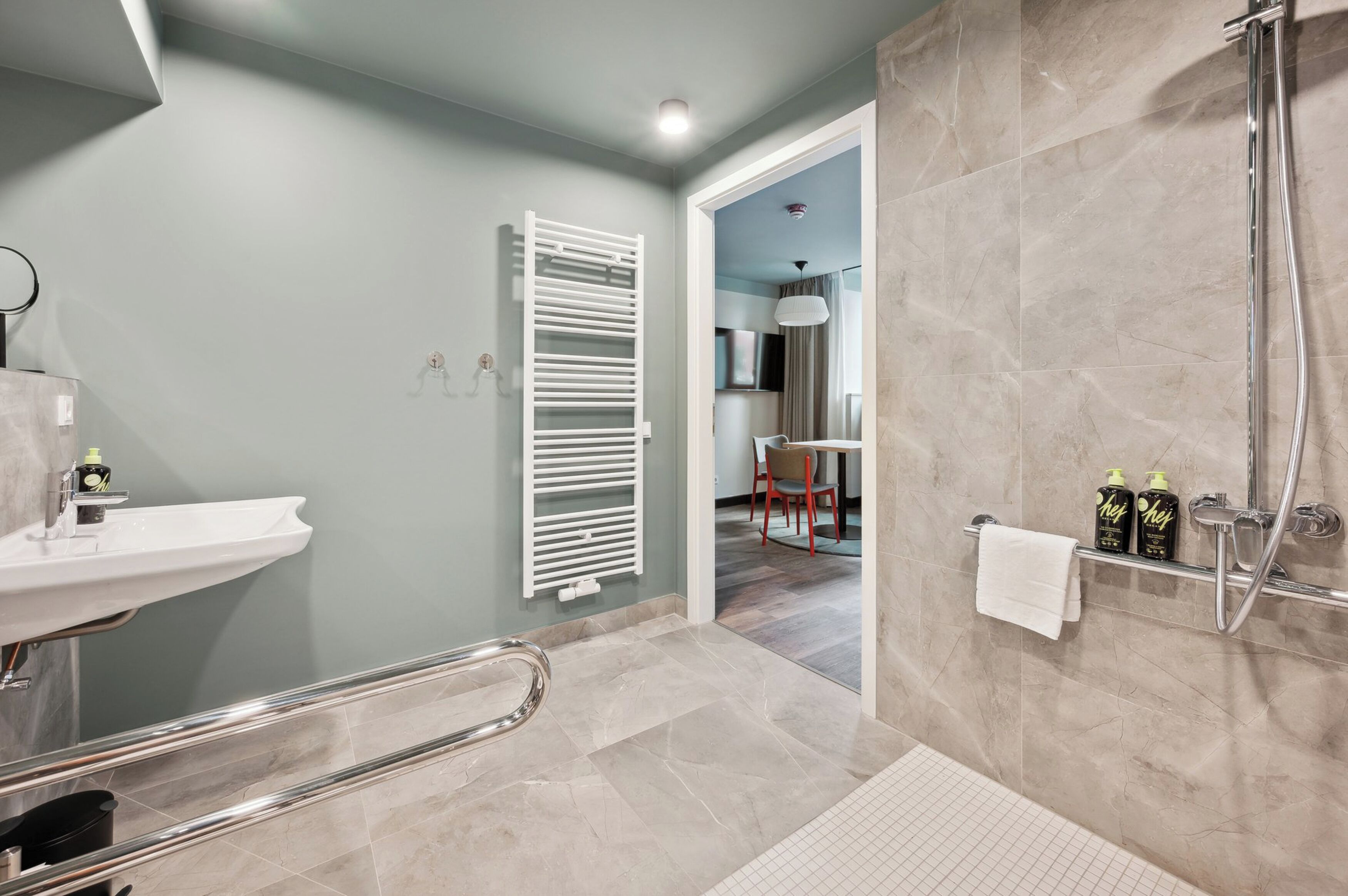 Une salle de bain moderne équipée d’un lavabo, d’une douche et d’un porte-serviettes.