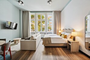 A modern hotel room with a bed, sofa, TV, and a large window with curtains. - Limehome Berlin Stresemannstr (Berlin)
