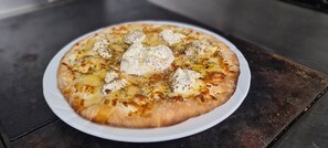 A pizza on a white plate. - LE 120 (La Chataigneraie)