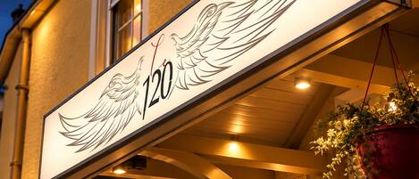 A building with a lit sign displaying the number 120 and a winged design.