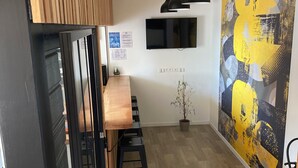 Eine moderne Küche mit Holztresen, schwarzen Barhocker, einem schwarzen Kühlschrank und einem großen abstrakten Gemälde an der Wand.