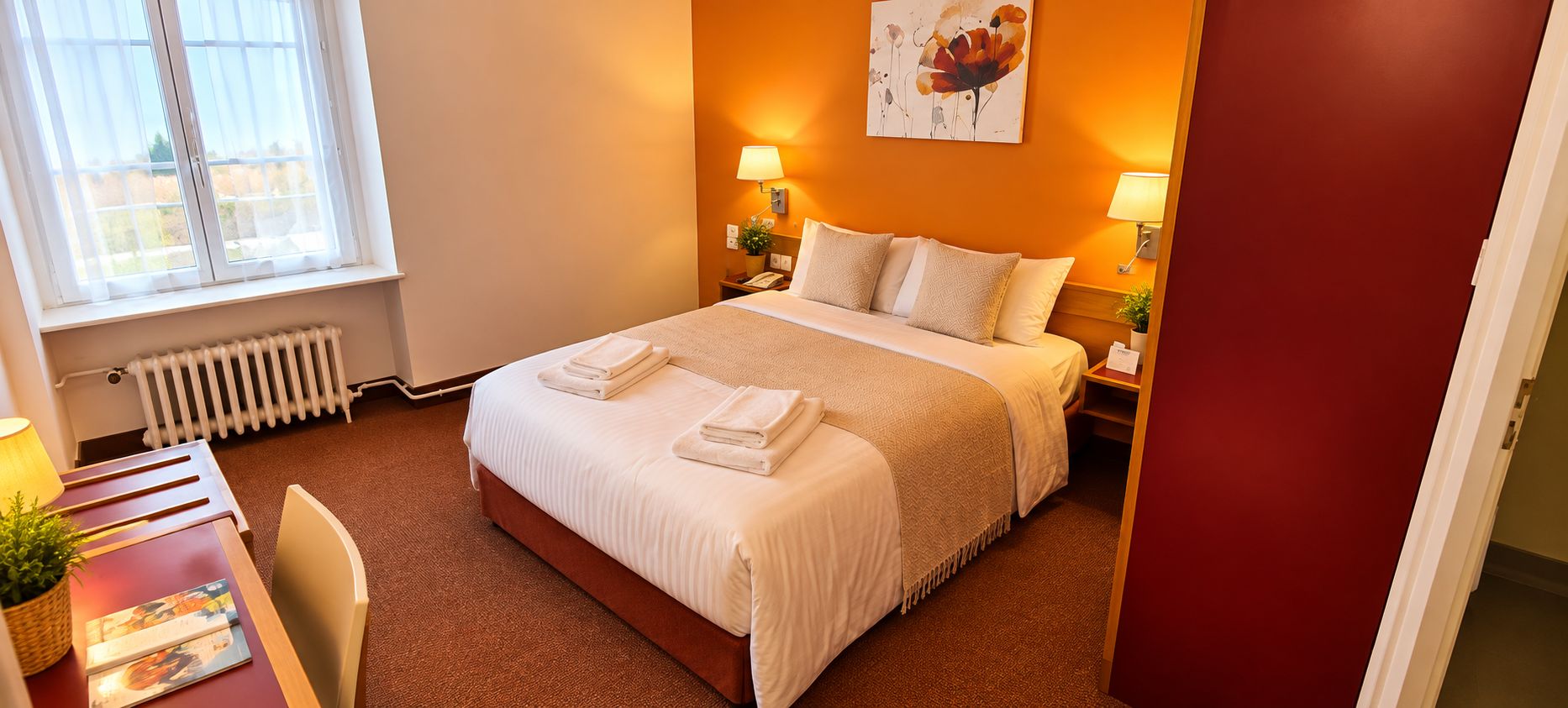 Una habitación de hotel con cama, mesitas de noche, radiador, ventana y un cuadro en la pared.