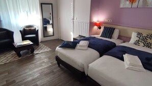 Ein Hotelzimmer mit zwei Betten, einem kleinen Tisch, einem Stuhl, einem Spiegel und einem Bild an der Wand.