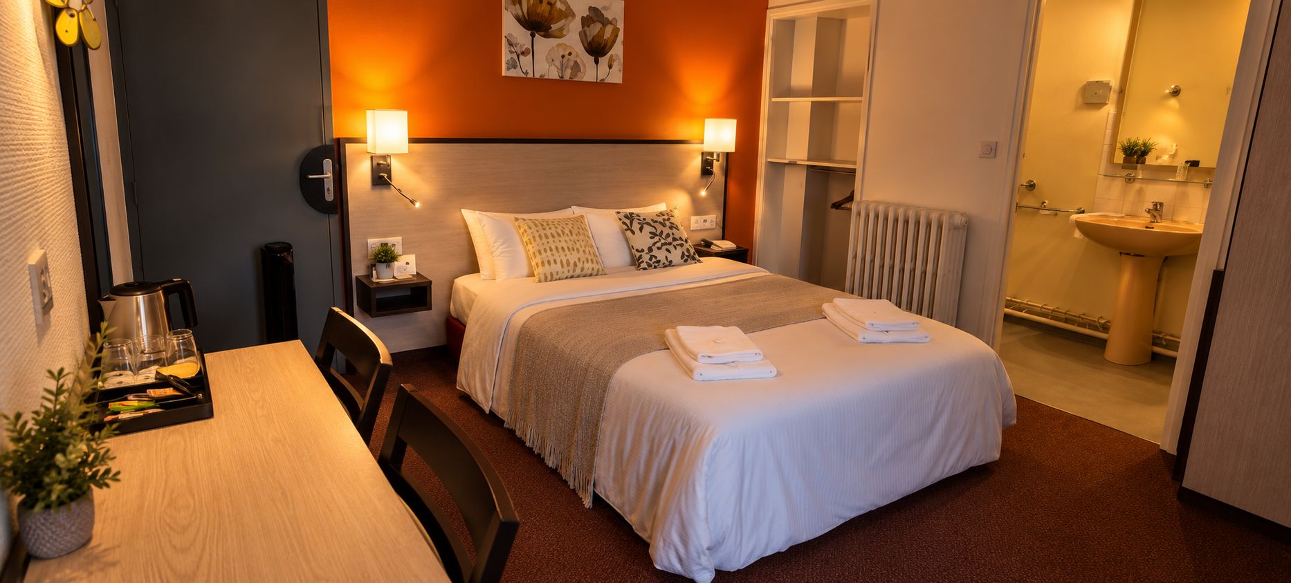 Ein Hotelzimmer mit Bett, Nachttischen, einem Tisch mit Pflanze und einem durchgegangenen Tür sichtbaren Badezimmer.