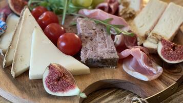 A wooden board with various cheeses, meats, and fruits.