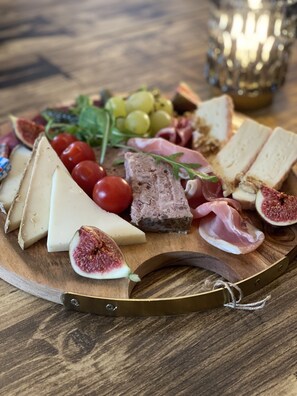 A wooden board with various cheeses, meats, and fruits. - LE 120 (La Chataigneraie)