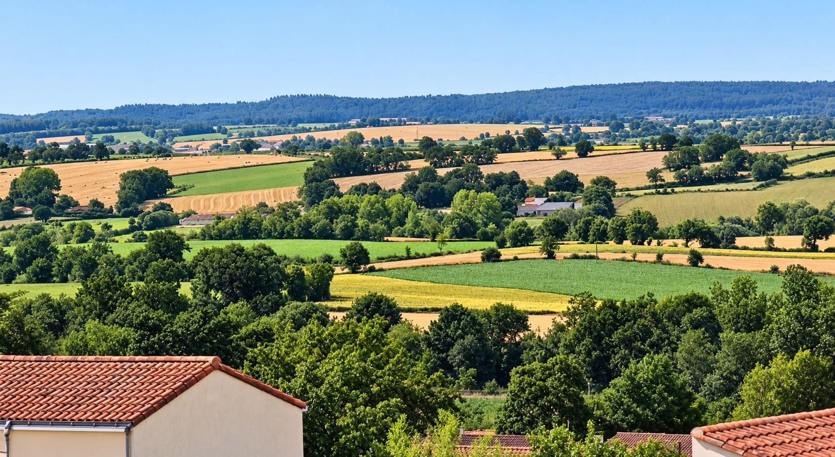 Paisaje rural con campos, árboles y un edificio con techo de tejas rojas.