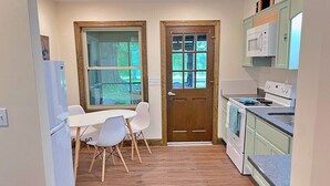 A compact kitchen with a dining area, wooden flooring, and light green cabinets. - The Ocoee Casita - Less then 5 minutes from Lee University  (Cleveland)