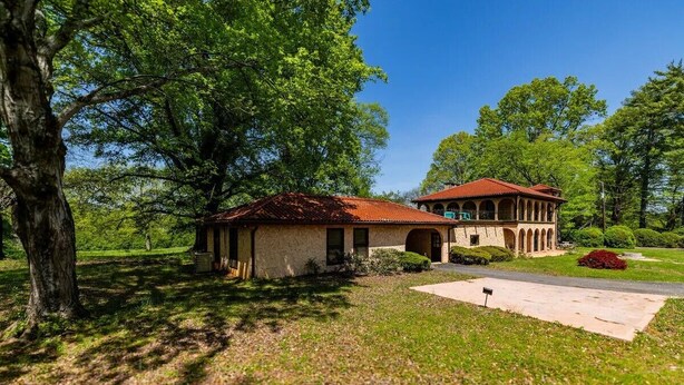A two-story building with a red-tiled roof, surrounded by lush greenery and trees. - The Ocoee Casita - Less then 5 minutes from Lee University  (Cleveland)
