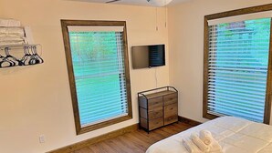 A bedroom with two windows, a flat-screen TV, a wooden dresser, and a bed with a white comforter. - The Ocoee Casita - Less then 5 minutes from Lee University  (Cleveland)