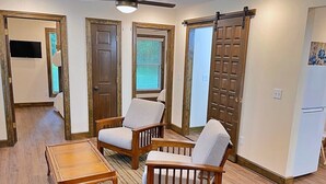 A living room with a sofa, two armchairs, a coffee table, a television, and a sliding door. - The Ocoee Casita - Less then 5 minutes from Lee University  (Cleveland)