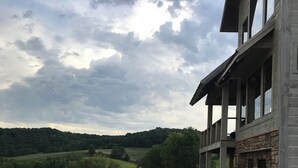 A building with a stone facade and multiple windows, surrounded by a gravel area and a grassy field. - Stunning Lodge Experience in Buffalo County WI/Picturesque Views-Pet Friendly! (Mondovi)
