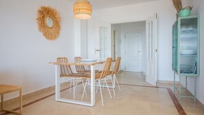 Uma área de refeições com mesa de madeira e cadeiras de vime, luminária pendente e um armário verde com uma planta.