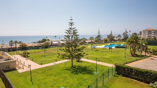 A resort with a pool area, palm trees, and a view of the sea. - La Noria apartment 11 2a (Manilva)
