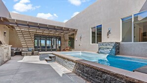A modern outdoor pool area with a stone wall, lounge seating, and a pergola. - Serenity: Private Pool + Golf + Sand Dunes (Hurricane)