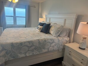 A bed with a patterned bedspread, a headboard, and two bedside lamps.