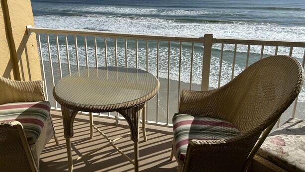 A balcony with wicker furniture and a view of the ocean. - Ocean Front Condo (New Smyrna Beach)
