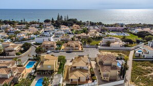 A coastal residential area with houses, a swimming pool, and a view of the sea. - Villa Ribeiro by HelloVacations (Albufeira)