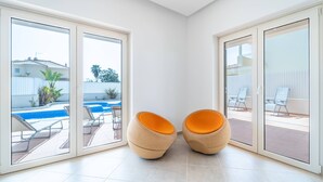 A modern room with large sliding glass doors leading to an outdoor pool area. - Villa Ribeiro by HelloVacations (Albufeira)