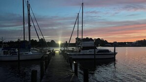 A marina at sunset with boats docked along a wooden pier.